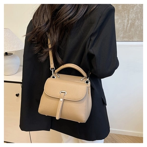 Close-up of khaki litchi grain leather handbag with silver hardware and shoulder strap
