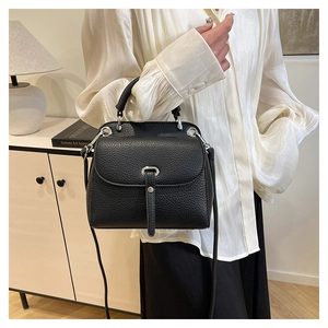 Detail of black lychee grain leather handbag with silver hardware and shoulder strap