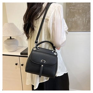 Close-up of black litchi grain leather shoulder bag with silver ring buckle and flap
