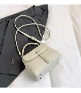 Detail of cream lychee texture bag with flap cover and metal rivets on soft bedding