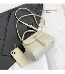 Mini beige lychee leather bag detail with phone comparison for size reference