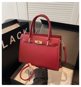 Detail of red textured leather handbag with gold lock and black gift packaging set