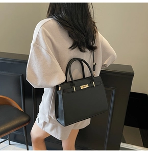Classic black leather handbag with gold hardware shown as a shoulder bag on a model