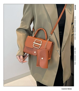 Detail of a brown leather crossbody bag set with gold hardware on a model with a blazer