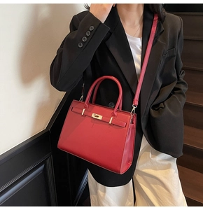 Detail view of red lychee texture handbag with golden buckle and detachable strap
