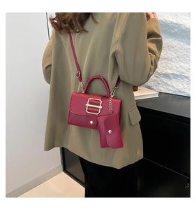 Detail of burgundy lychee leather handbag with gold decorative buckle and small pouch