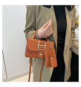 Detail of orange-brown leather square bag with large gold buckle and mini purse attachment