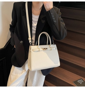 Detail of elegant cream leather handbag with gold metal clasp on a wooden staircase