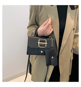 Detail of black lychee grain leather handbag with gold buckle and mini pouch accessory