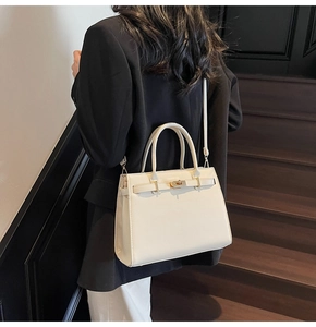 Creamy white structured leather bag shown on model highlighting size and crossbody strap