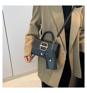 Detail of black lychee leather crossbody bag with gold metal clasp and mini pouch