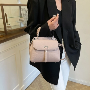 Elegant light pink litchi grain leather handbag with metal buckle and shoulder strap