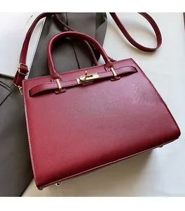 Macro detail of wine red pebbled leather texture and gold hardware on the Kelly bag