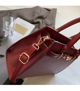 Detail of dark red textured leather handbag with elegant gold hardware and adjustable strap