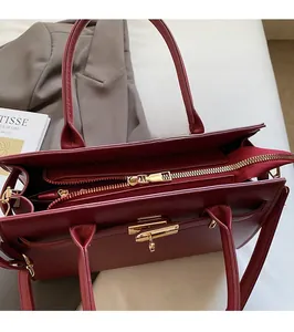 Close-up of smooth golden metal zipper and cross-pattern texture on burgundy Kelly bag