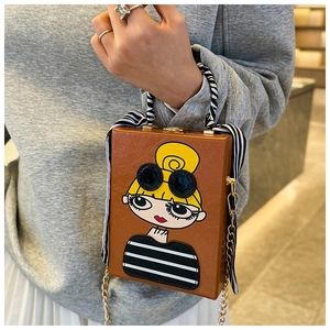 Brown box bag with cartoon girl design and striped silk handle held by a model