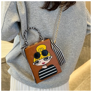 Detail of box clutch bag with cartoon girl portrait and silk scarf handle detail