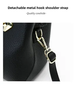 Detail of gold-tone metal hook buckle on black litchi grain leather bag with detachable strap