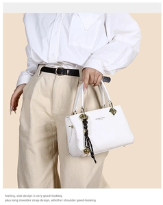 Close-up of white leather tote bag with pebble texture and gold hardware detailing