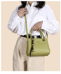 Detailed view of avocado green leather tote bag with silk scarf and gold bell charm detail