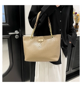 Detail of khaki woven texture tote bag with golden chain strap and cat pendant