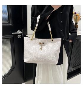 Close-up of cream woven tote bag with gold chain strap and elegant deer pendant detail