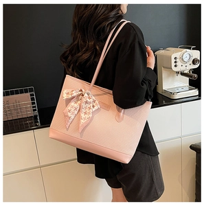 Detailed view of pink woven tote bag with houndstooth scarf and brand logo plate