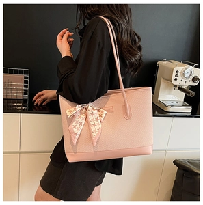 Pink woven tote bag with checkered bow scarf shown on model in a modern cafe setting