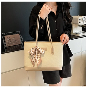 Close-up of beige woven tote bag with a chic houndstooth scarf on the handle