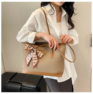 Detail of khaki woven tote bag with brown leather trim and houndstooth silk scarf accent