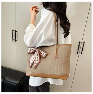 Detail of a large woven tote bag with brown leather trim and chic houndstooth scarf accent