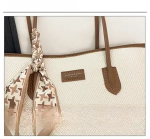 Detail of canvas tote bag with brown leather trim and houndstooth patterned scarf