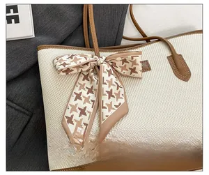 Close-up of woven tote bag featuring brown leather trim and decorative silk scarf detail