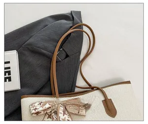 Close-up of beige woven tote bag with brown leather straps and houndstooth silk scarf