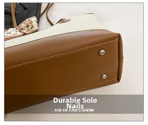 Detail view of wear-resistant metal feet and stitching on bicolor tote bag base