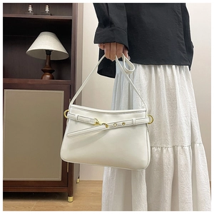 Détail du sac fourre-tout blanc avec boucle dorée tenu par un mannequin en intérieur