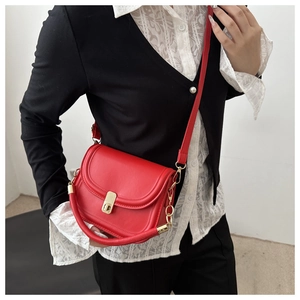 Close-up of red leather saddle bag featuring a gold metal buckle and stylish shoulder strap
