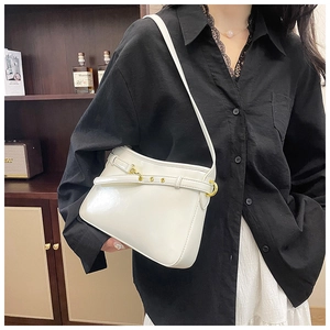 Détail du sac à bandoulière blanc brillant avec chaînes dorées et ceinture à œillets