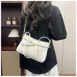 Détail du sac cabas en cuir blanc crème avec boucle dorée sur une chemise noire