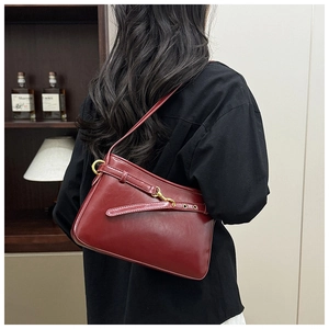Détail du sac à bandoulière en cuir brillant bordeaux avec boucle et détails dorés