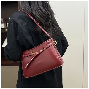 Détail du sac à bandoulière en cuir brillant bordeaux avec boucle en métal doré