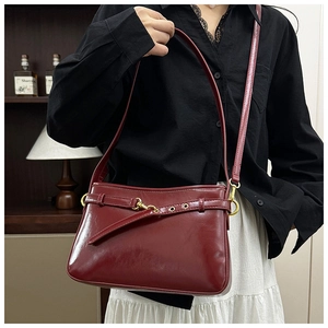 Détail d'un sac cabas vintage en cuir bordeaux avec boucle métallique porté par un mannequin