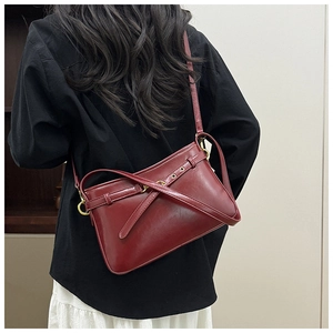 Détail du sac bandoulière en cuir bordeaux avec boucle dorée et sangle porté par un mannequin