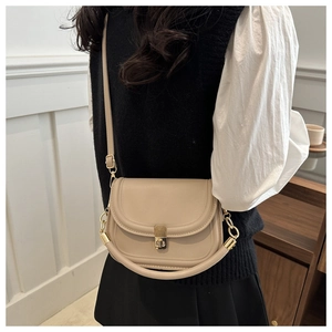 Detail of a beige PU leather saddle bag with vintage gold knob buckle and shoulder strap