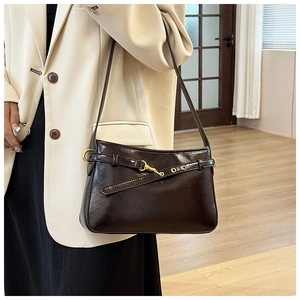 Détail du sac cabas en cuir marron foncé avec boucle dorée sur blazer beige