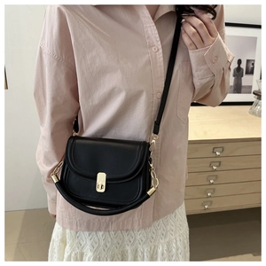 Detail of black semi-circular saddle bag with gold metal clasp and chain strap