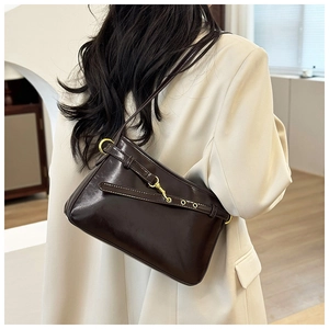 Détail d'un sac à bandoulière en cuir lisse marron foncé avec boucle dorée sur un mannequin