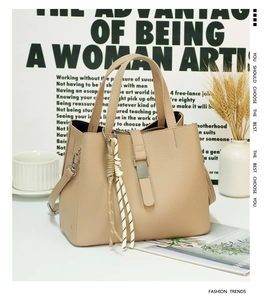 Close-up of beige lychee grain leather handbag with woven rope detail and metal buckle