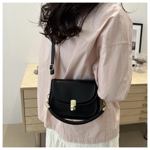 Detail of black saddle bag with gold rectangular lock and curved top handle