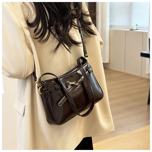 Détail d'un sac à bandoulière en cuir marron foncé avec boucles dorées et sangle décorative